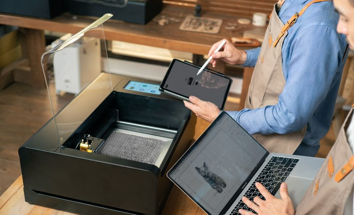 Operators use laptop and tablet to programme a Flux laser machine
